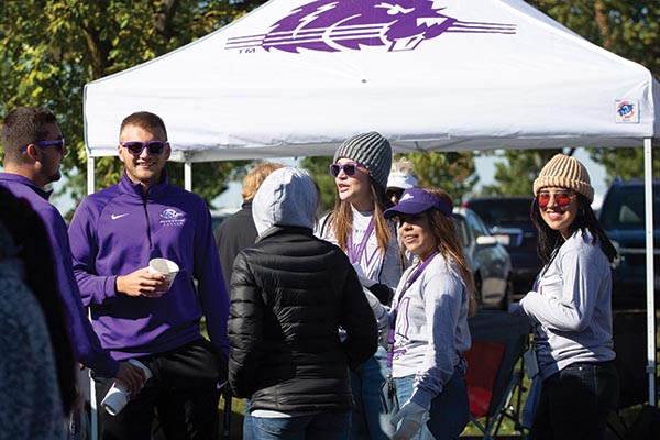 Bluffton University Homecoming with alumni standing in the tail-gating zone and chatting